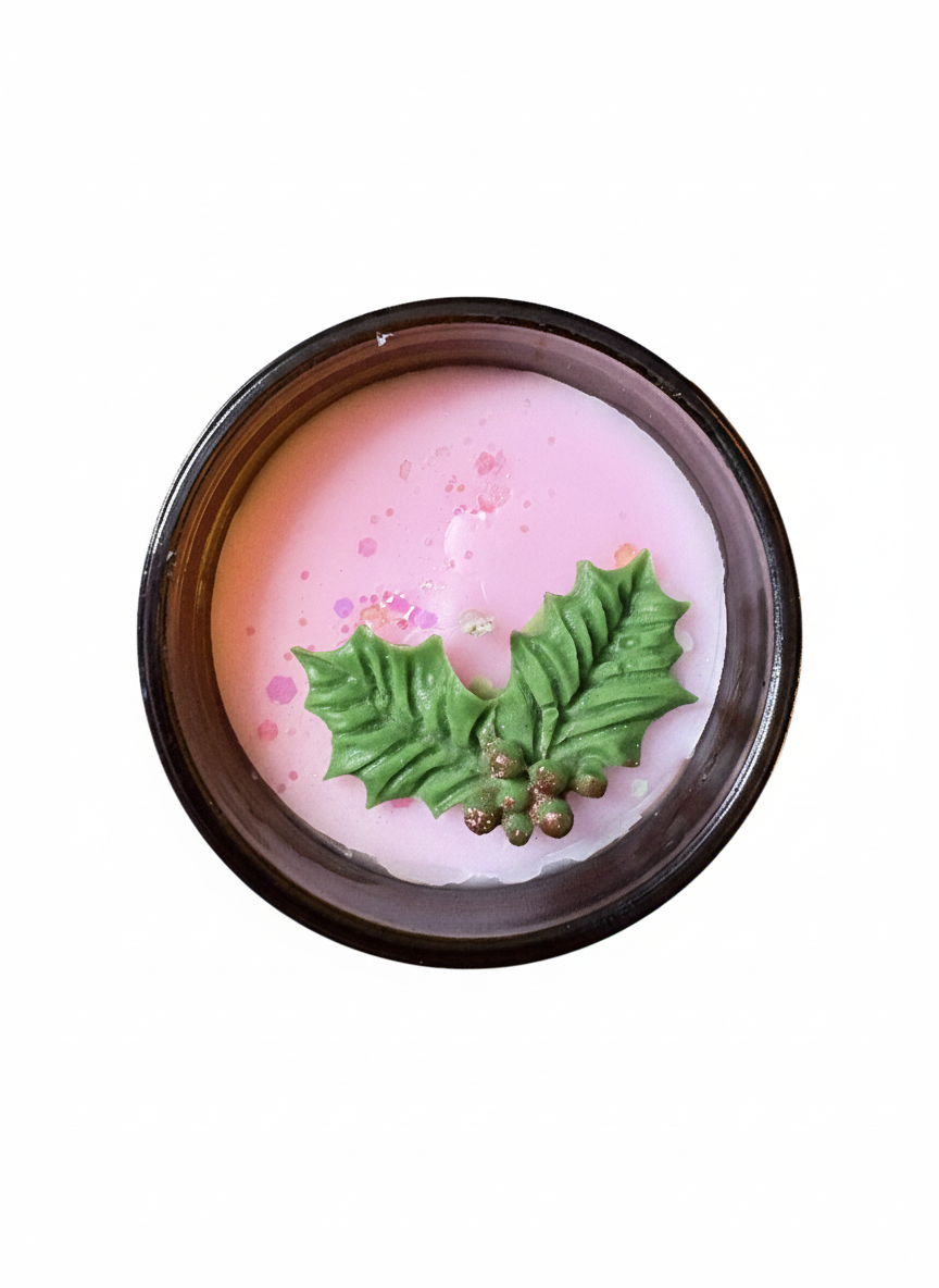 Pink candle with green holly leaves on a white background