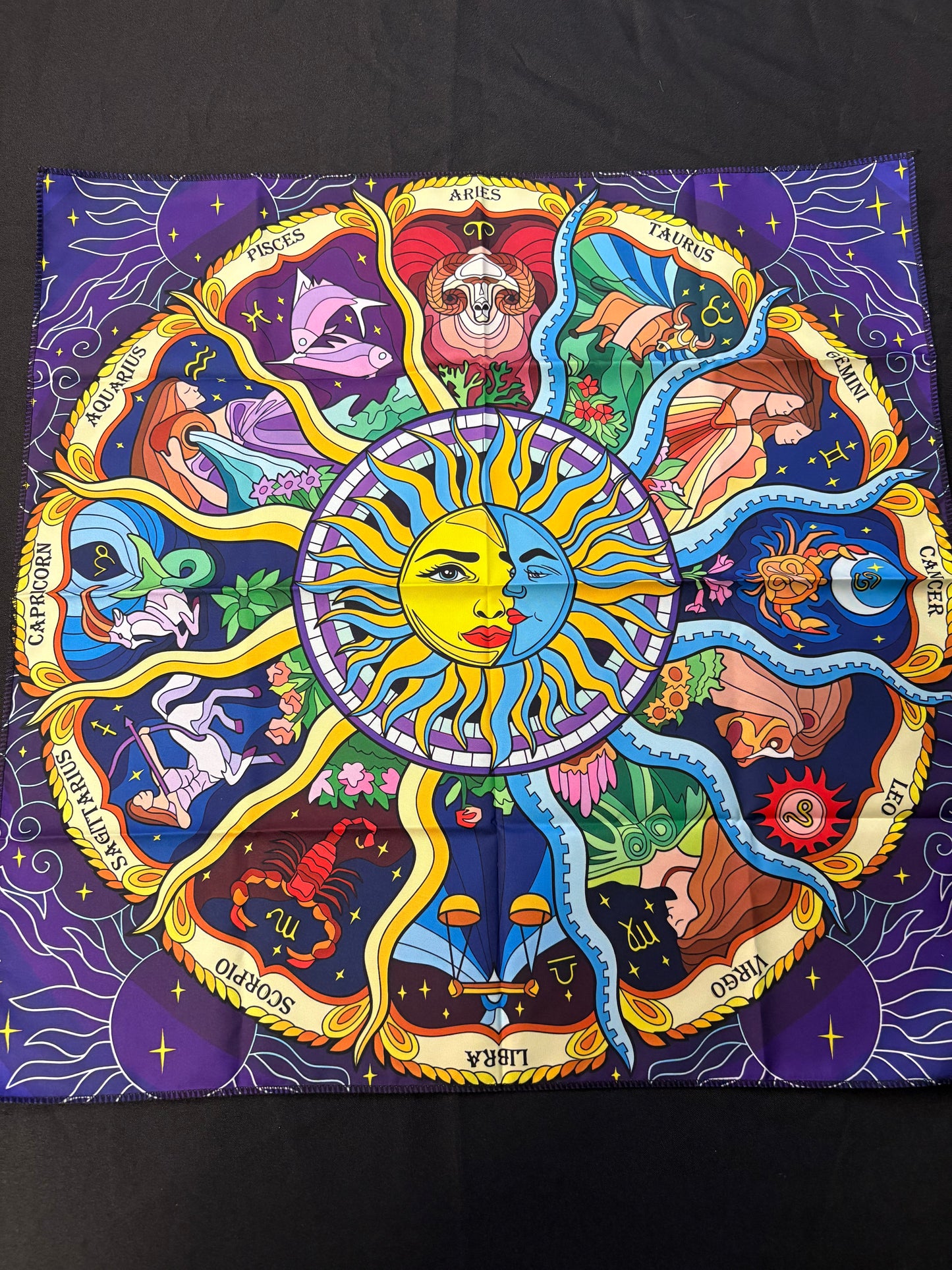 Colorful zodiac art piece with a central sun and moon design on a dark background