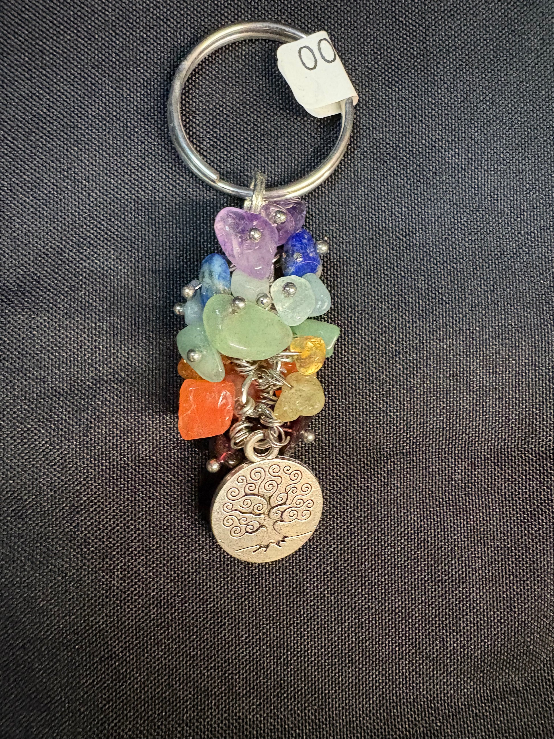Keychain with colorful beads and a tree of life charm on a dark fabric background