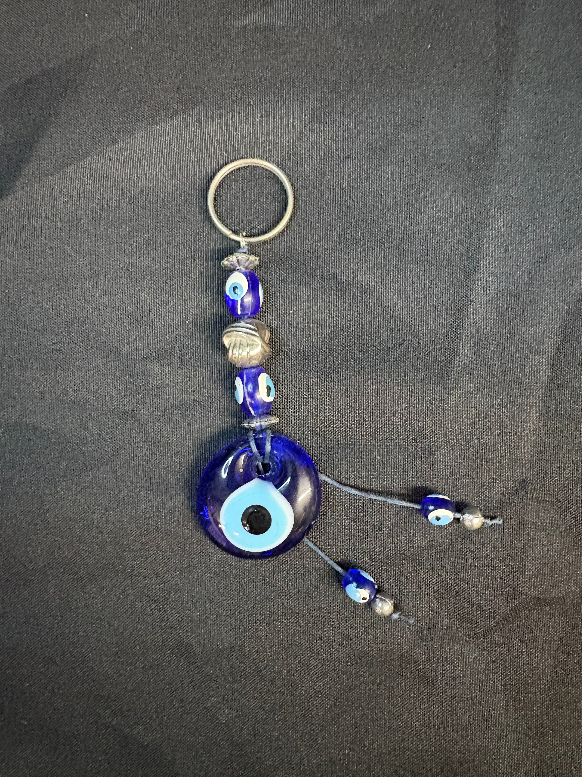 Blue evil eye keychain with beads on a dark surface