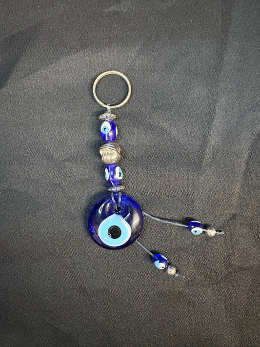 Blue evil eye keychain with beads on a dark surface