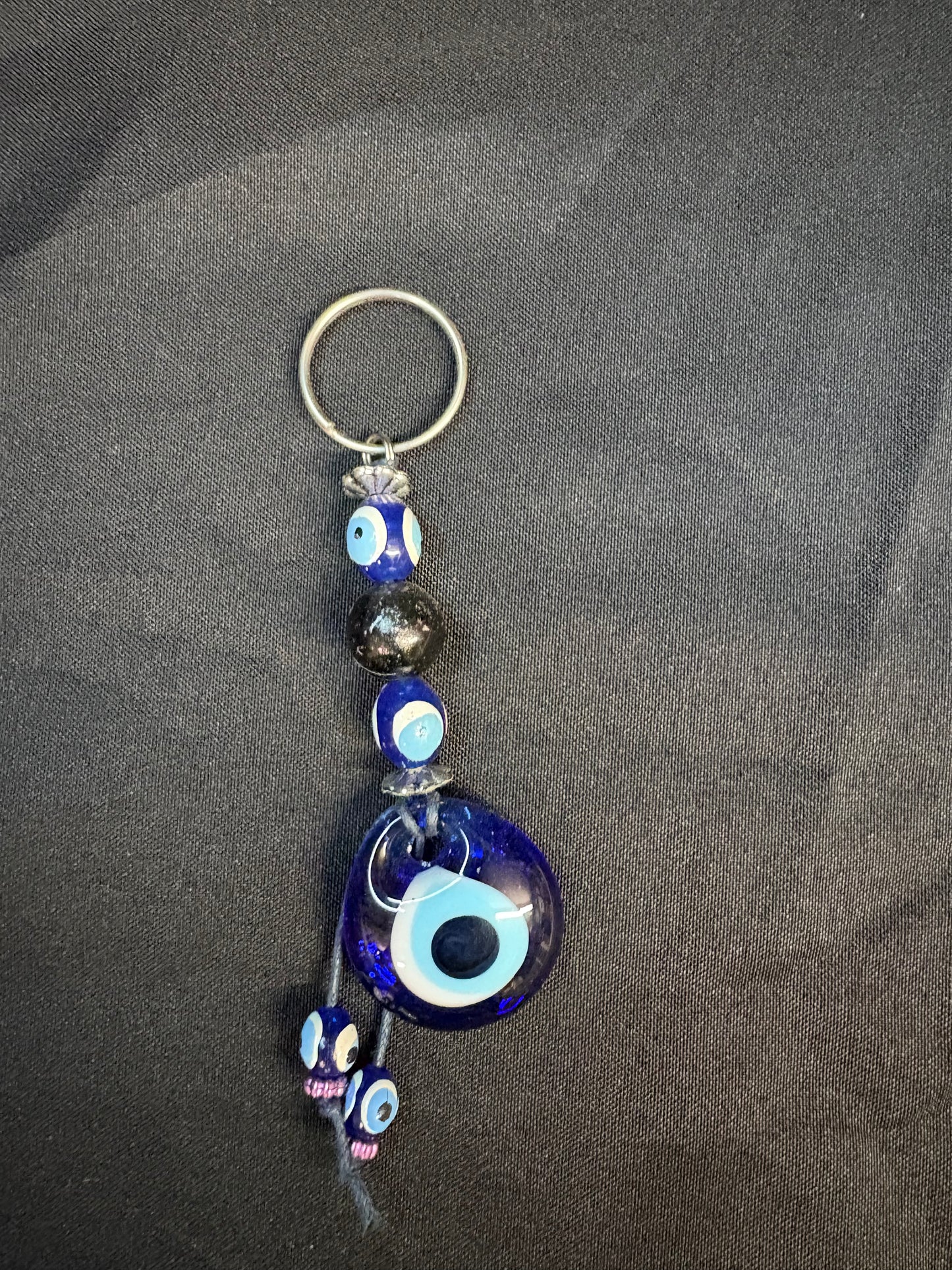 Keychain with blue evil eye design on a dark fabric background