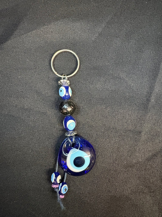 Keychain with blue evil eye design on a dark fabric background