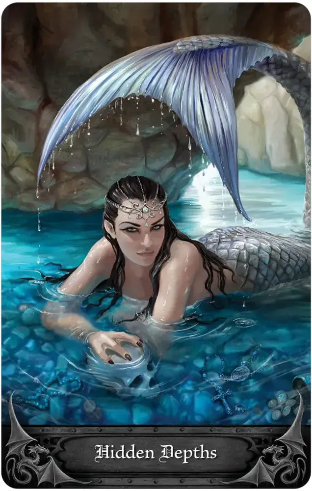 Mermaid with a blue tail emerging from water, surrounded by rocks and underwater plants.