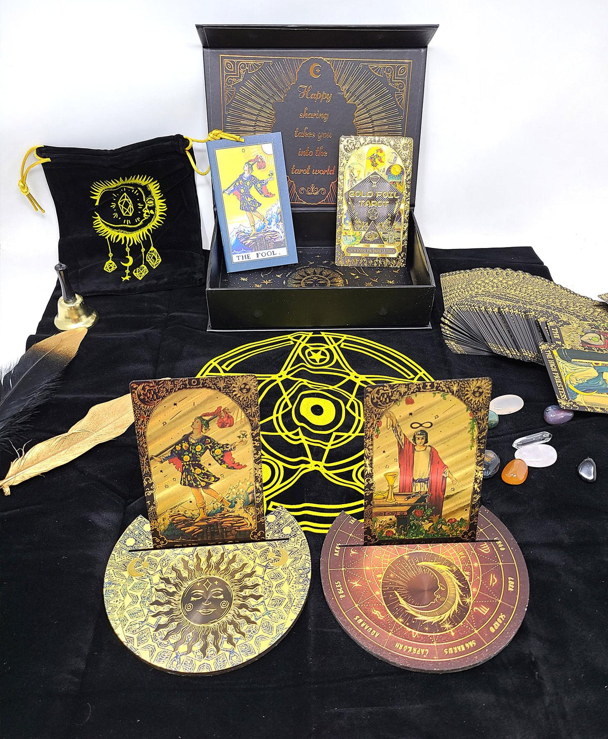 Collection of tarot cards, a bag, and crystals on a black cloth with a white background